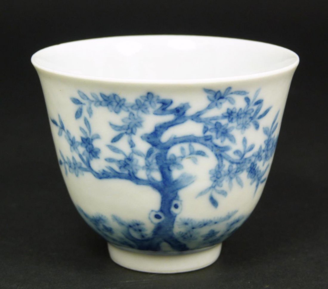 CHINESE KANGXI EGGSHELL PORCELAIN TEA BOWL: Chinese hand painted blue and white eggshell porcelain bowl depicting tree with blooming flowers and calligraphy poem to verso. Bottom holds blue six character Kangxi reign mark. Measures 2" x 2 1/2" 