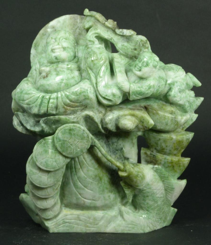 CHINESE SOAPSTONE BUDDHA FIGURE: A Chinese hand carved green soapstone group figure depicting a seated happy Buddha with attendant and fish with coins. Measures 8 1/2" height x 71/2" width (21.6cm x 19cm). Total weight of 2953 grams.