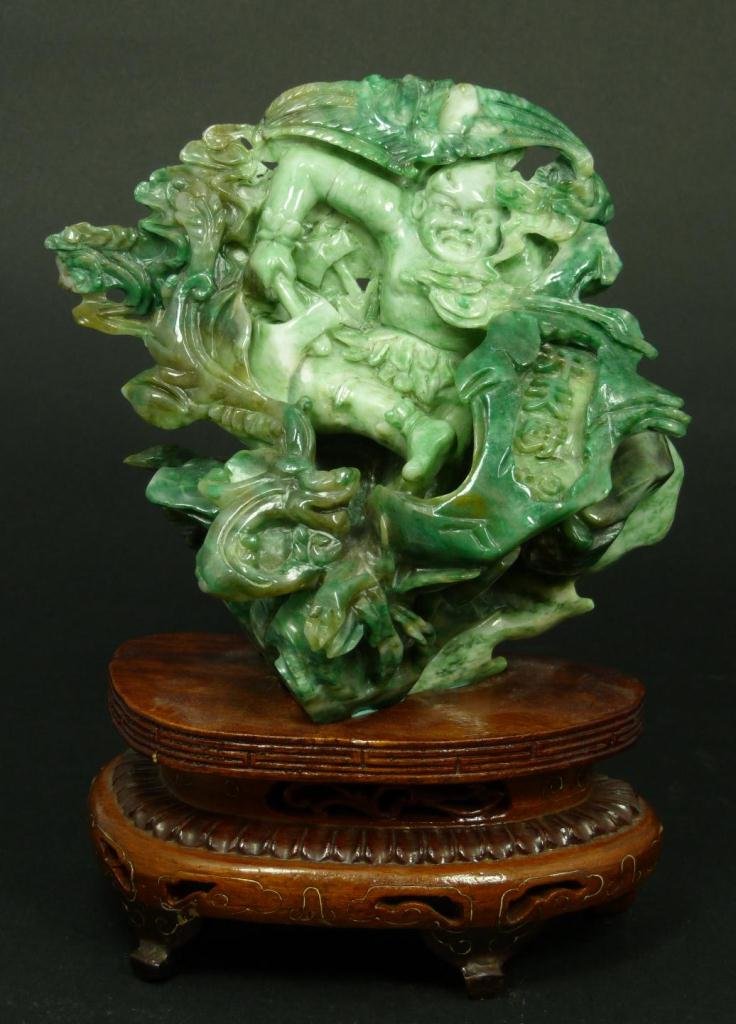 CHINESE RELIEF CARVED JADEITE WARRIOR GROUP: A Chinese relief carved jadeite group depicting a tribal warrior with axe. Scene also depicts bats, clouds, trees and rock formations. Raised four character calligraphy marks to lower right in recess.