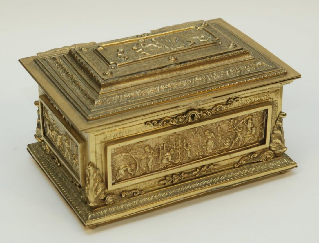SPANISH CAST BRONZE JEWELRY CASKET: Spanish cast bronze jewelry casket having raised children scene. Bottom holds impressed MADE IN SPAIN mark. Measures 7 1/4" height x 12" width x 8 3/4" depth (18.4cm x 30.5cm x 22.2cm).