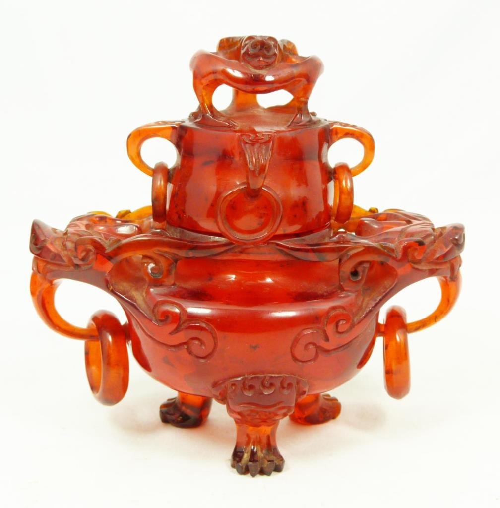 CHINESE CHERRY AMBER CHIH LUNG DRAGONS URN: Chinese carved cherry amber urn having Chih Lung dragon finial to cover and four handles with relief rings. Two figural dragon head handles to sides of body, each holding ring. Hollowed interior and c