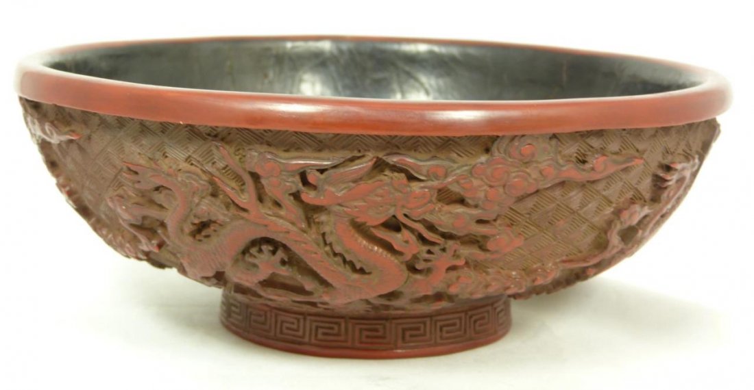 ANTIQUE CHINESE CINNABAR LACQUERED BOWL: Antique Chinese cinnabar red lacquered bowl depicting flying dragons amongst clouds. Black lacquer interior and bottom. Bottom holds etched six character calligraphy Ming Dynasty Jiaqing reign mark. C
