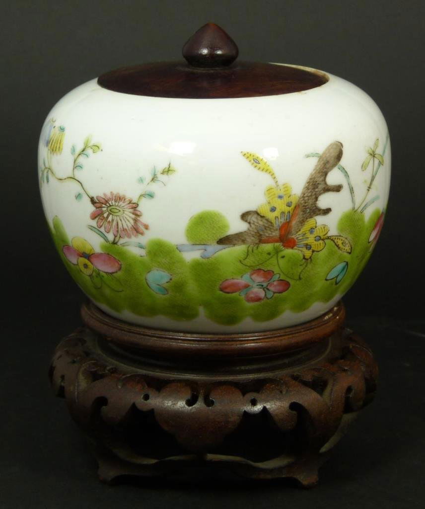 CHINESE FAMILLE ROSE COVERED GINGER JAR: Chinese hand painted enameled covered ginger jar depicting insects. Wooden cover. Bottom holds four character calligraphy reign mark. Includes fitted round wooden base. Measures 4" height + 2 1/8" bas