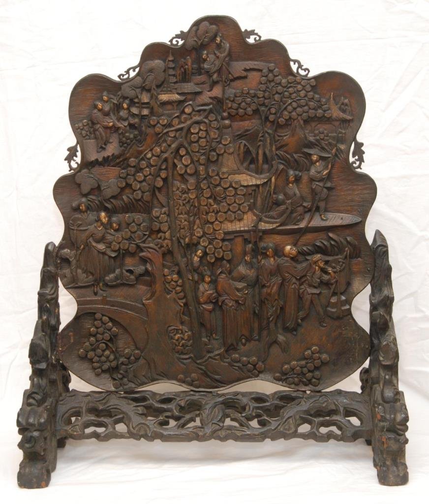 CHINESE RELIEF CARVED WOODEN PLAQUE SCREEN: A large and finely carved wooden Chinese relief plaque depicting a village scene with gold paint to faces and trees. Figural leaf back design. Mid to late Qing Dynasty period, 18th/19th century. Measu