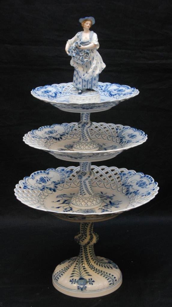 19th C MEISSEN PORCELAIN BLUE ONION CAKE STAND: A Meissen German porcelain Blue Onion three tier cake plate having figural woman with flowers finial. Bottom holds blue crossed swords mark with number 2. Circa 1860-1880. Measures 21 1/2" height (54.