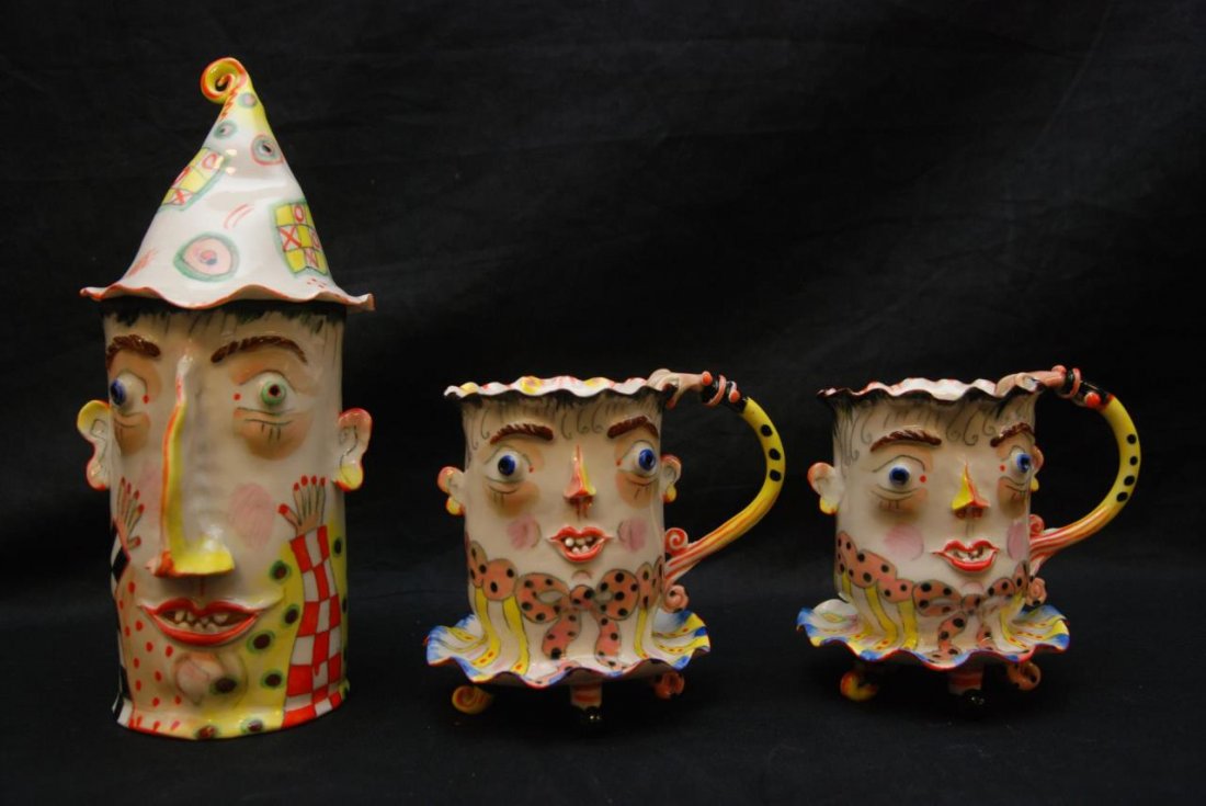 IRINA ZAYTCEVA PORCELAIN FIGURAL TEA SET: A three piece figural tea set by Irina Zaytceva (RUSSIAN, 1957-). Set includes a covered pitcher and two footed tea cups. Each has a figural face and hand handle design with Irina's signature style. E