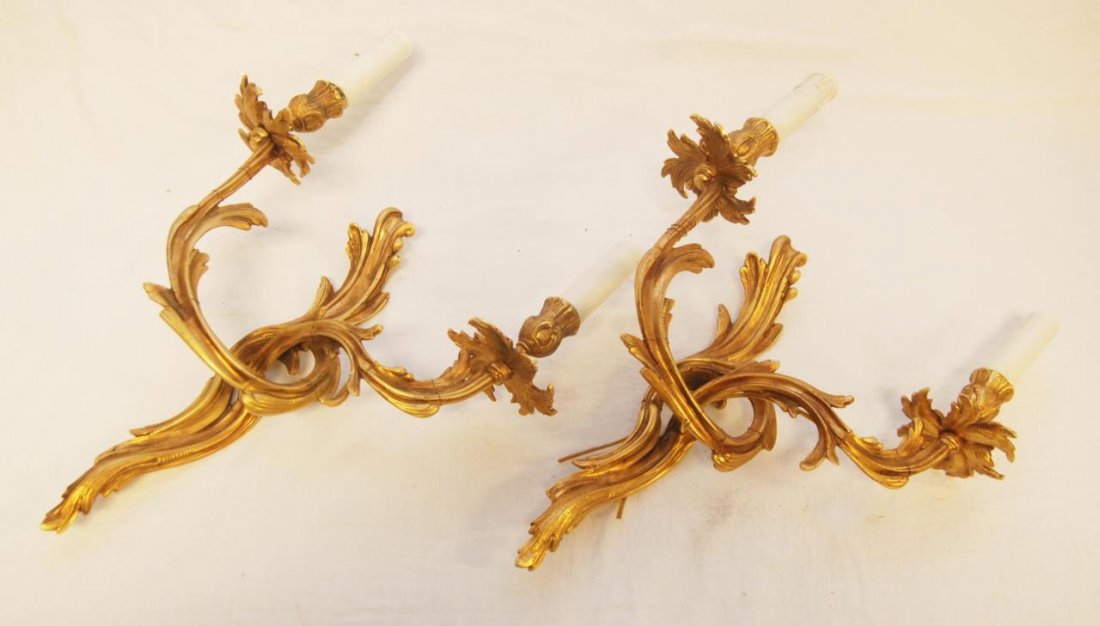 PAIR OF DORE BRONZE TWO LIGHT WALL SCONCES: Pair of dore bronze two light wall sconces. Each one with scrolled foliate arms and measures approx. 13" (33 cm) height. Provenance: From the Estate of Count and Countess Claes-Eric de Lewenhaupt of S