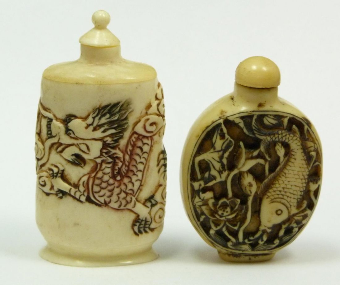 TWO CARVED BONE FIGURAL SNUFF BOTTLES: One depicts carved fish on one side and floral design on the other and the other one depicts a foo dragon. Measures 3" (7.5 cm) height. 86 grams.