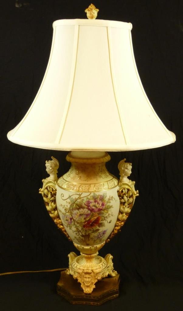 RUDOLSADT PORCELAIN FIURAL LAMP: Rudolstadt porcelain hand painted lamp with two figures on each side . Has floral decorations and gilt work throughout. Three feet with faces as each one. Sits on a gild metal reticulated base. Overal