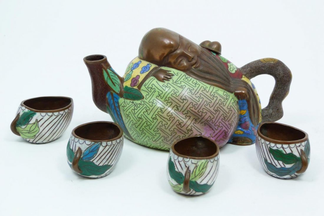 CHINESE CLOISONNE BRONZE BUDDHA TEAPOT: Chinese enameled bronze cloisonne teapot having a figural design with Hotei Buddha sleeping on a peach. Includes four leaf form tea cups. 19th/20th century. Tallest measures 3 1/4" height (8.2cm).