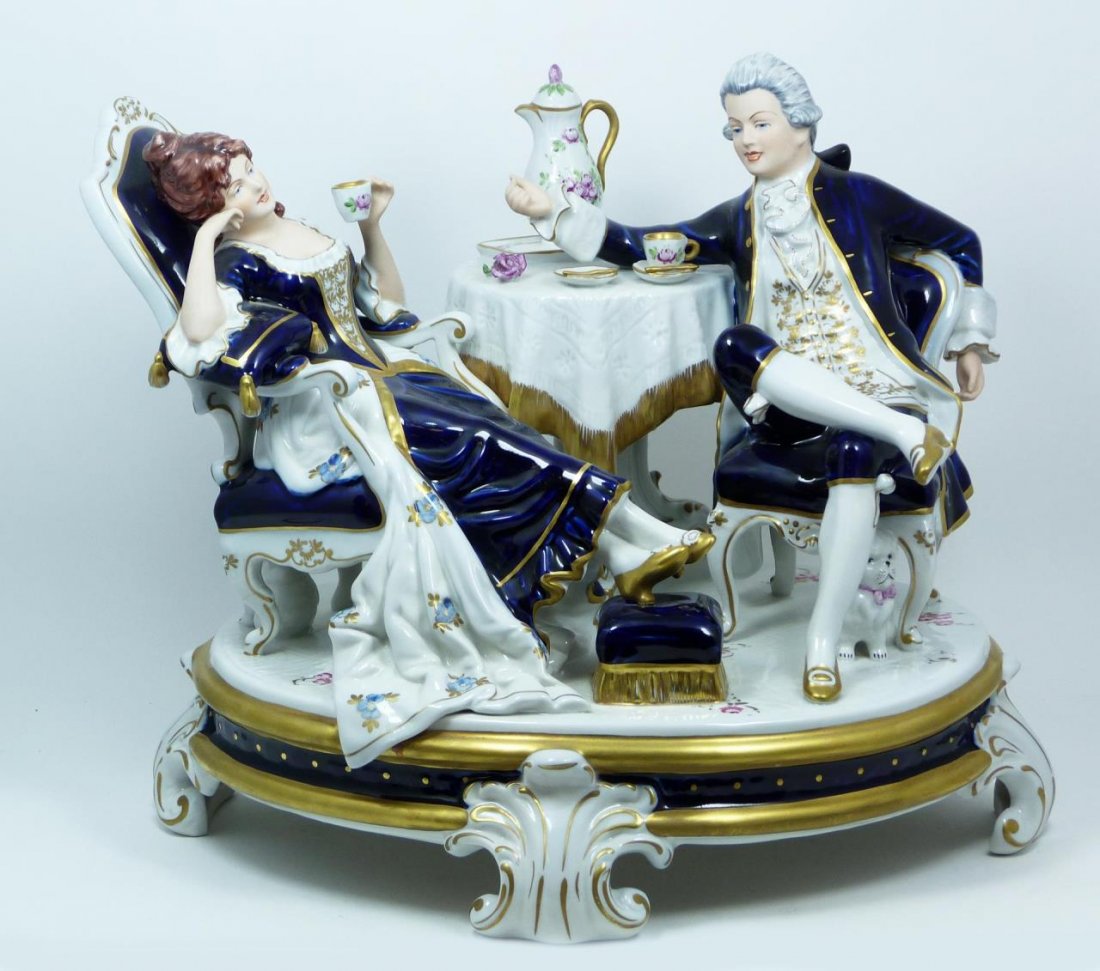 ROYAL DUX PORCELAIN FIGURAL GROUPING: Royal Dux porcelain figural group. The life like expressions and body language of the couple depict them casually enjoying each others company. Has cobalt coloration, rose decorated china, and little 