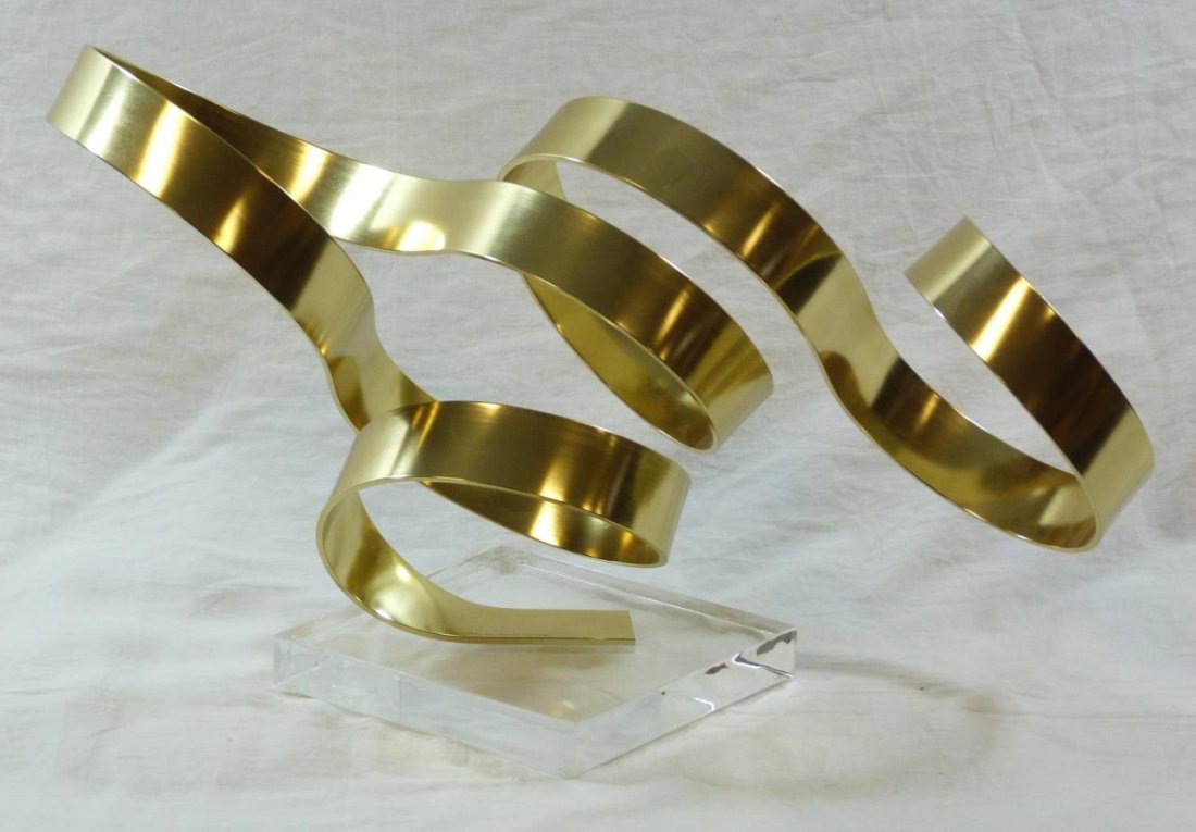 DAN MURPHY ABSTRACT RIBBON BRASS SCULPTURE: Vintage brass ribbon sculpture on Lucite base. Signed Dan Murphy Dated 1981. Beautiful polished finish. Measures approx. 11 3/4" (30 cm) height and approx. 20" (50 cm) wide. 1687.3 grams.