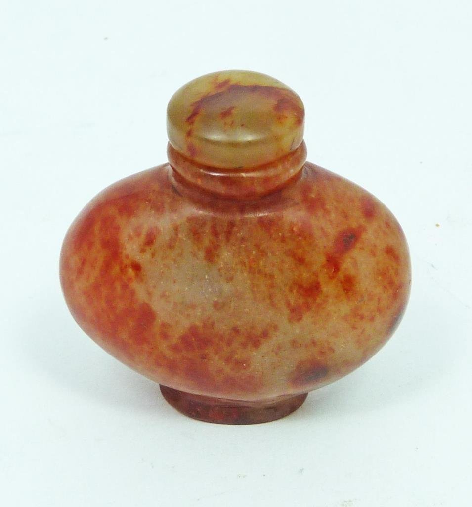 CHINESE CARVED CARNELIAN SNUFF BOTTLE: A Chinese hand carved carnelian snuff bottle. Red to clear mottled colors. 19th/20th century. Measures 2 1/4" height (5.7cm).