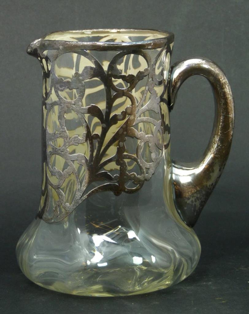 HAND BLOWN CRYSTAL & STERLING OVERLAY PITCHER: A hand blown crystal pitcher with floral scrolled sterling silver overlay design. Bottom marked 1069 2510. Circa late 19th to early 20th century. Measures 6 7/8" height (17.4cm). Total weight of 27.91