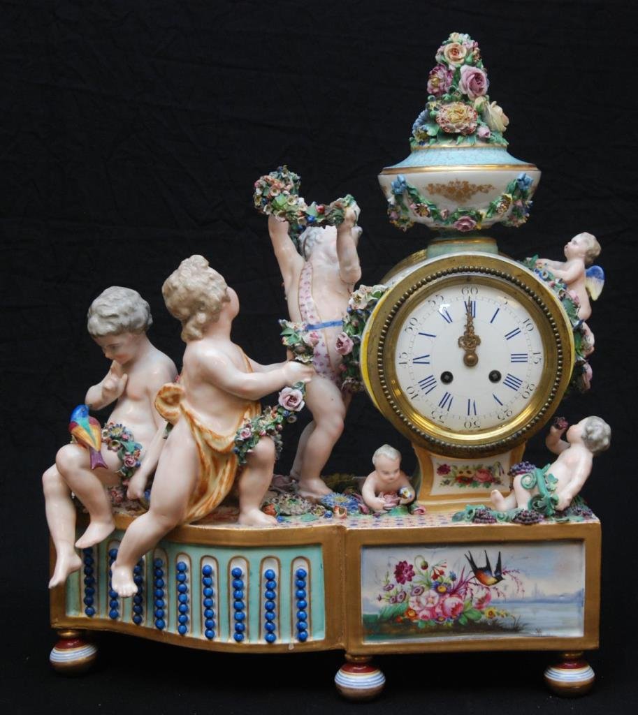 ANTIQUE MEISSEN PORCELAIN FIGURAL CLOCK GROUP: Antique Meissen German porcelain figural clock group depicting six cherubs with floral garlands and birds surrounding the clock case. Hand painted scenes with birds and flowers to base. White enamel f