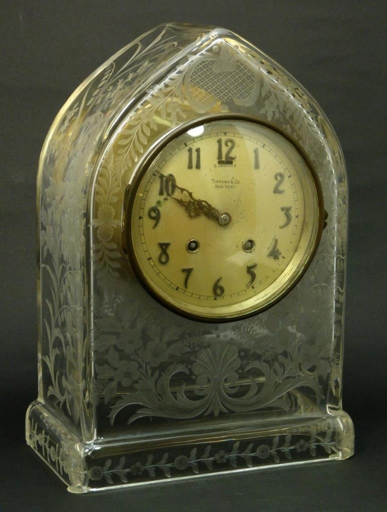 TIFFANY & CO FLORAL ETCHED CRYSTAL MANTLE CLOCK: A Tiffany and Company, New York etched crystal case mantel clock. Case having cut and frosted designs throughout with lattice to upper center. Silver tone face with applique bronze Arabic numerals. Sc