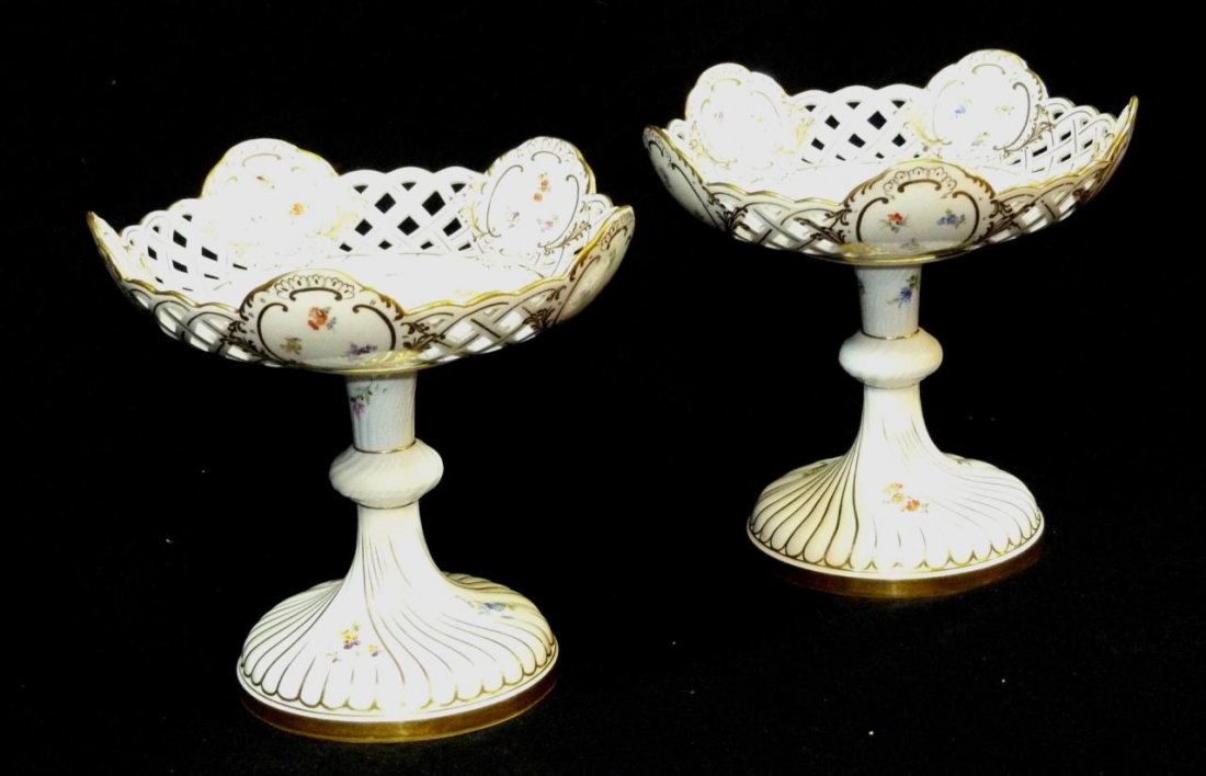 PAIR ANTIQUE MEISSEN FLORAL RETICULATED COMPOTES: A pair of antique Meissen German porcelain compotes having a reticulated lattice design with hand painted flowers. Each holding blue under glaze crossed swords marks to bottom. 19th century. Each appr