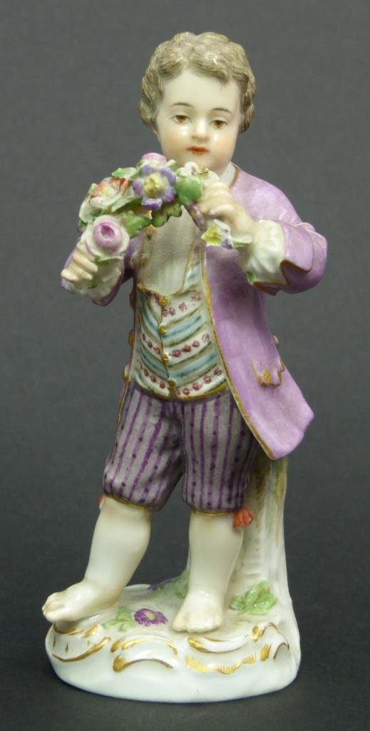 ANTIQUE MEISSEN PORCELAIN FIGURE OF BOY w FLOWERS: A Meissen German porcelian hand painted figure depicting a young boy holding flowers. Scrolled gold painted base. Bottom holds blue crossed swords marks with impressed 132. Measures 4 3/8" height (11.