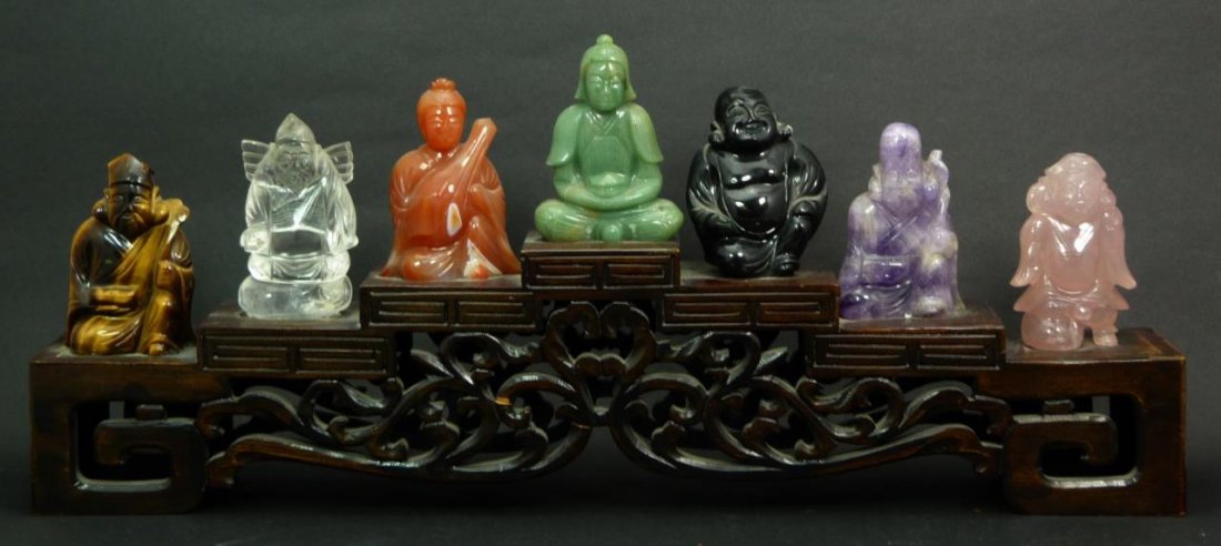 CHINESE 7 IMMORTALS VARIOUS STONE CARVED w BASE: A Chinese hand carved seven immortals assorted carved stone set. Figures carved with tiger eye, rock crystal, carnelian, jade, onyx, amethyst and rose quartz. Mounted on wood carved tiered base. Each 