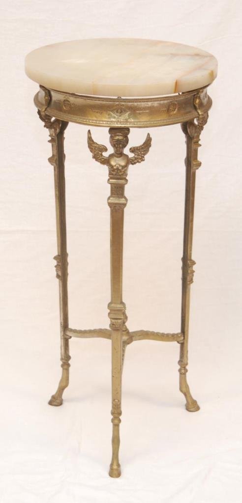 GILT ONYX TOP FIGURAL PEDESTAL TABLE: Gilded wrought iron onyx top figural round pedestal three legged table. Depicting angels on each leg with hooves as feet. Measures approx. 30 7/8" height x 14 5/8" diameter (78.4cm x 31.14cm). Provena