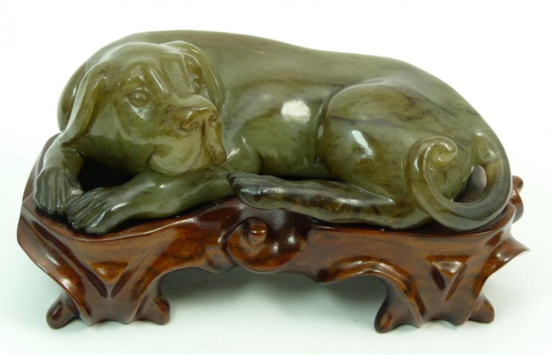 CARVED JADE FIGURE OF SLEEPING DOG: CARVED JADE FIGURE OF SLEEPING DOG 20th C figurine carved of Jade. Measures 5" long (12.7cm) comes with raised fitted base. Weighs 627g
