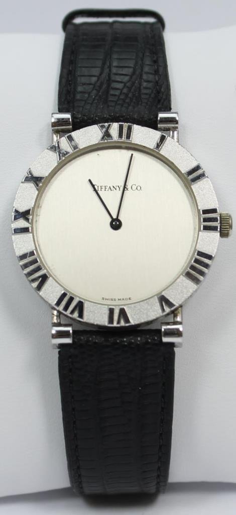 GENUINE TIFFANY & Co. STERLING CASE WRIST WATCH: A genuine Tiffany & Company sterling silver case watch having a raised Roman Numeral design. Verso marked and numbered D286753. Has black lizard leather band. Case measures approx. 1 1/8" diameter.