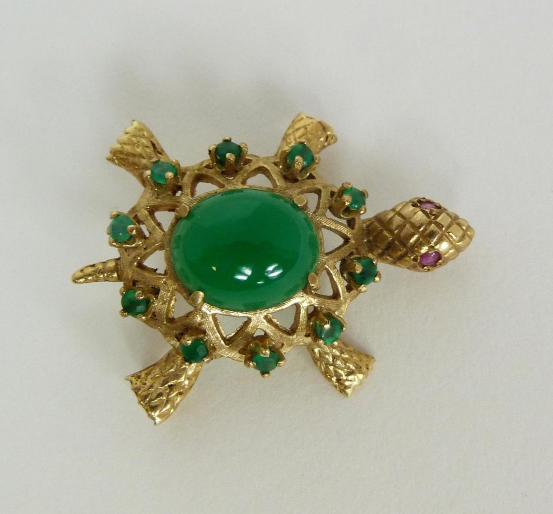 14K YG JADEITE EMERALD AND RUBY FIGURAL TURTLE PIN: A beautiful ladies 14k yellow gold figural turtle pendant featuring an oval cabochon cut even toned translucent emerald green jadeite approx. 12.1mm x 10.1mm x 4.9mm, 6.00ct. to back of shell. Ten rou