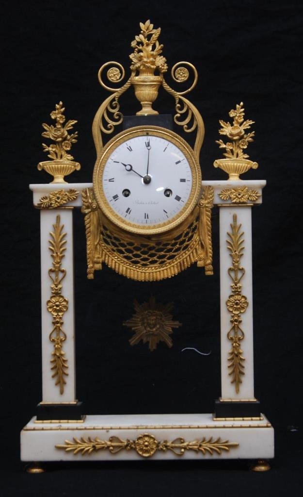 ANTIQUE FRENCH MARBLE & GILT ORMOLU CLOCK: "Babin A. Corbeil" on porcelain face. French with two square columns and ormolu mounts. Includes three fleur de lis baskets on top and drape below face. Sunburst with face pendulum. Face has Roman num