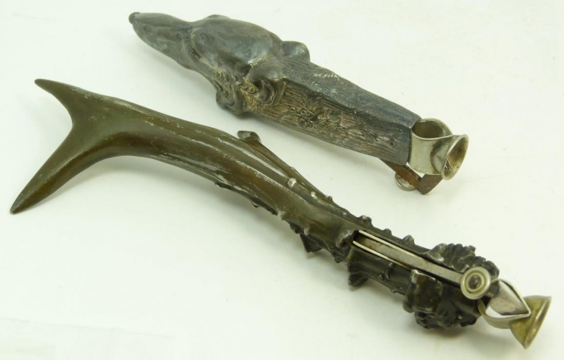 TWO LARGE ANTIQUE CIGAR CUTTERS: Tow large antique cigar cutters one depicts a dog and the other depicts a deer antler. Early 20th century. Longest measures approx 7 1/2" (19.05cm) Length. Total approx weight 228g.