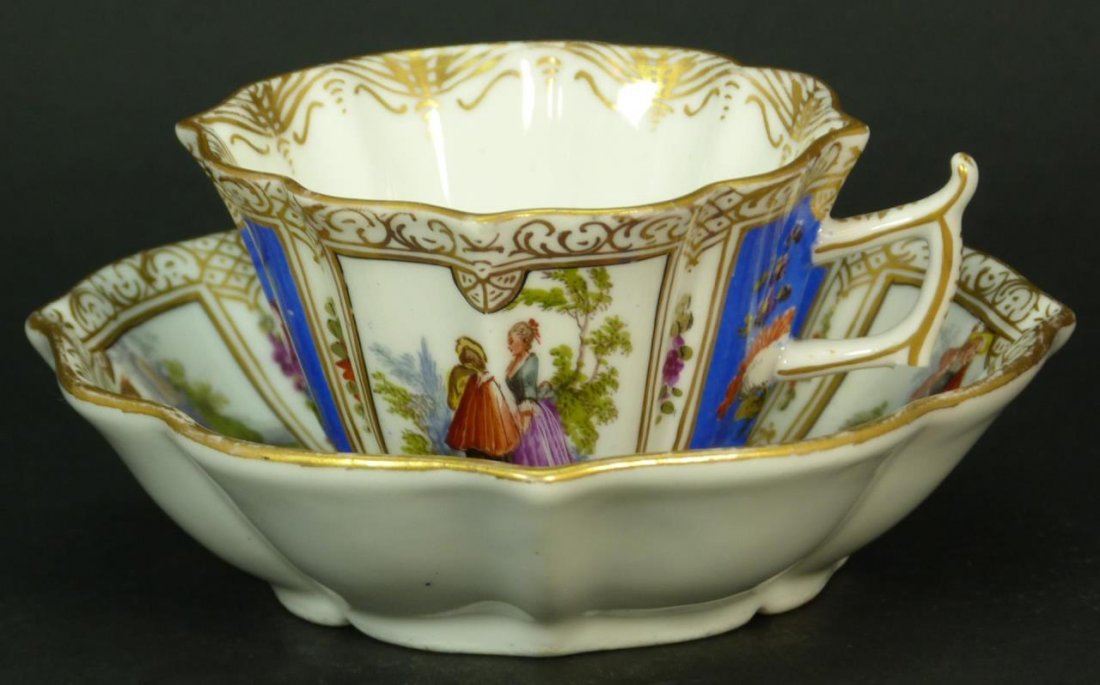 MEISSEN AUGUSTUS REX CUP & SAUCER: Meissen Augustus Rex porcelain cup and saucer hand painted with colonial scenes and a beautiful floral decor. Circa turn of the century. Saucer measures 5" (12.7cm) Diameter. Total approx weight 192g.