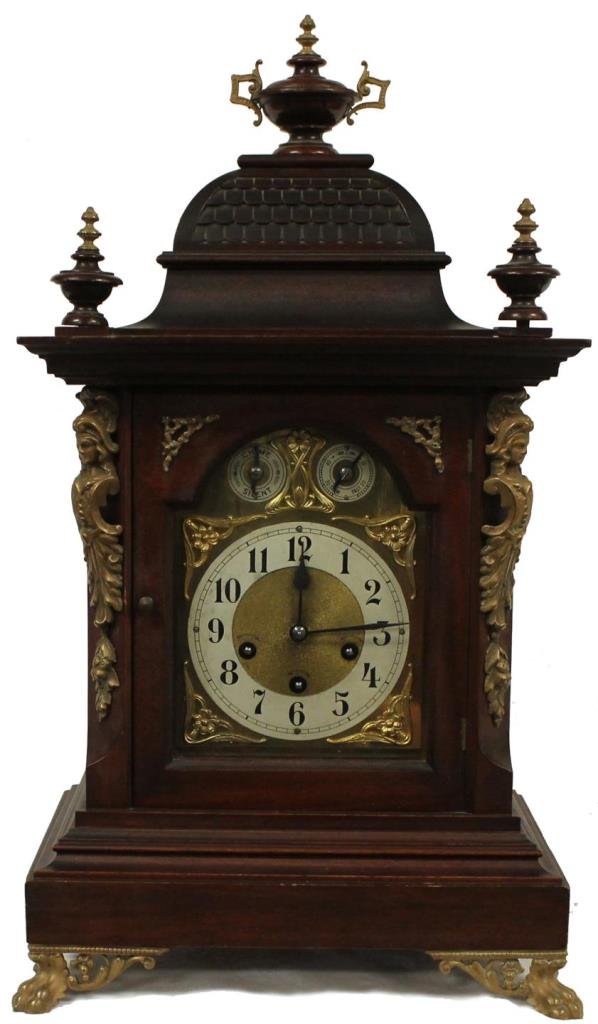 UNGHANS GERMAN 19TH CENTURY WOODEN MANTLE CLOCK: Clock has bronze mounts with lion's feet with bronze female figure head mounting to sides. Also with fitted wooden finial to top of clock. Has gold plated aluminum face. Dates to early 20th century. M