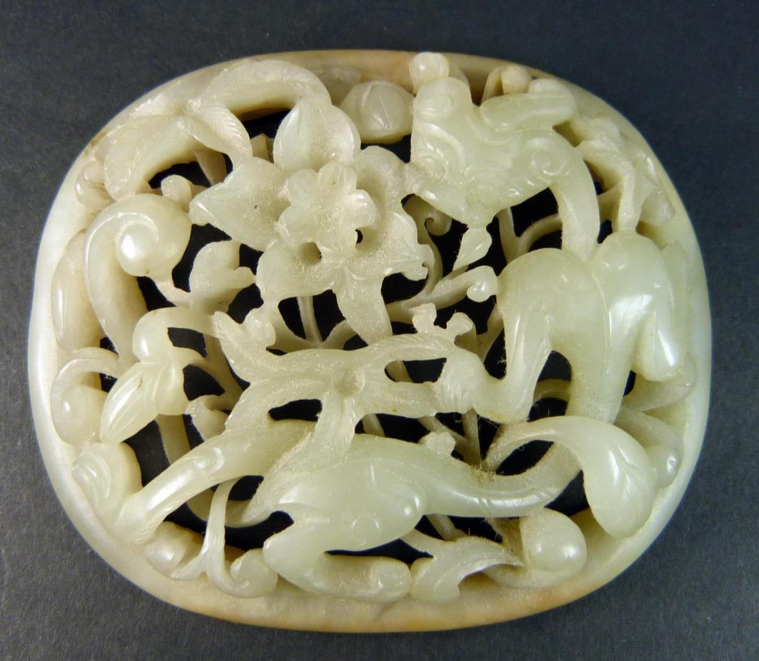 EARLY QING PERIOD CHINESE WHITE HETIAN JADE PLAQUE: Exquisitely carved Chinese early Qing dynasty period fully reticulated oval plaque depicting foo lion with lotus blossoms. Even white tone throughout with some russet mottling. Measures approx. 3" len