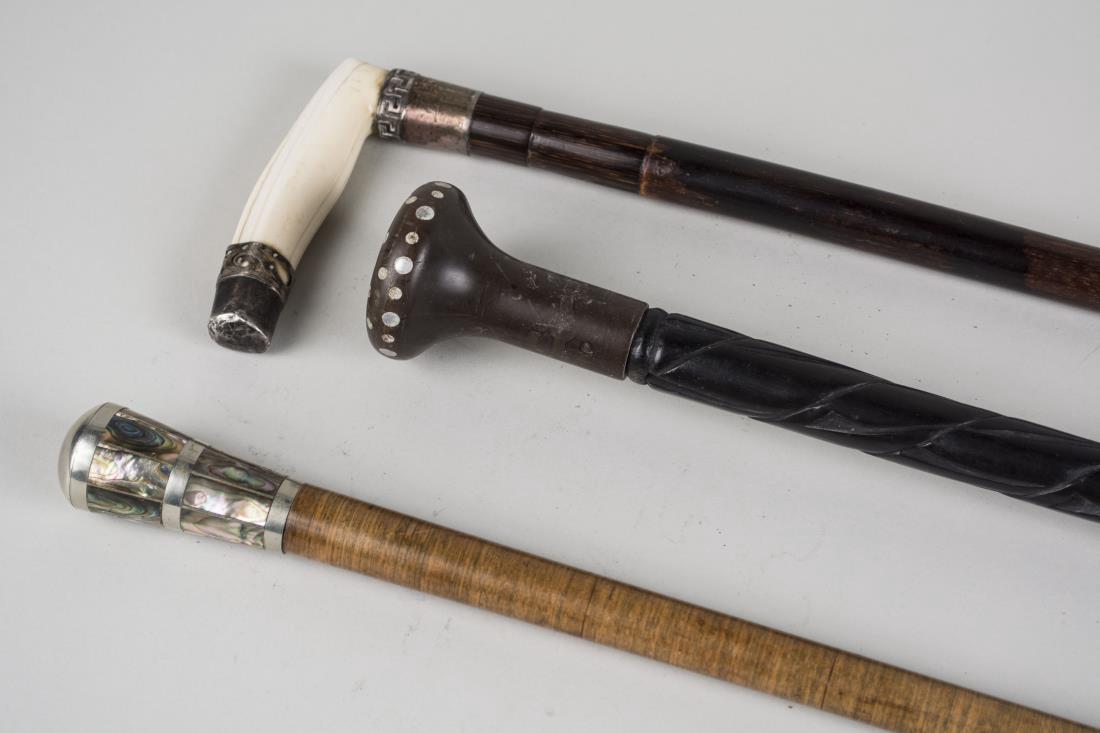 Three Walking Sticks: One, carved ebonized wood stick, one with bone handle and one with abalone inset handle. Tallest, height 36 inches. Notice to bidders: Condition reports and additional photographs are provided by requ