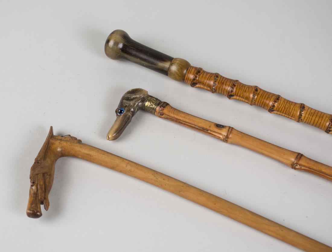 Three Vintage Walking Sticks: One with carved horsehead and man's face, signed, two faux bamboo, one with horn handle and the other a dog's head with glass eyes. Tallest, height 36 inches. Notice to bidders: Condition reports and 