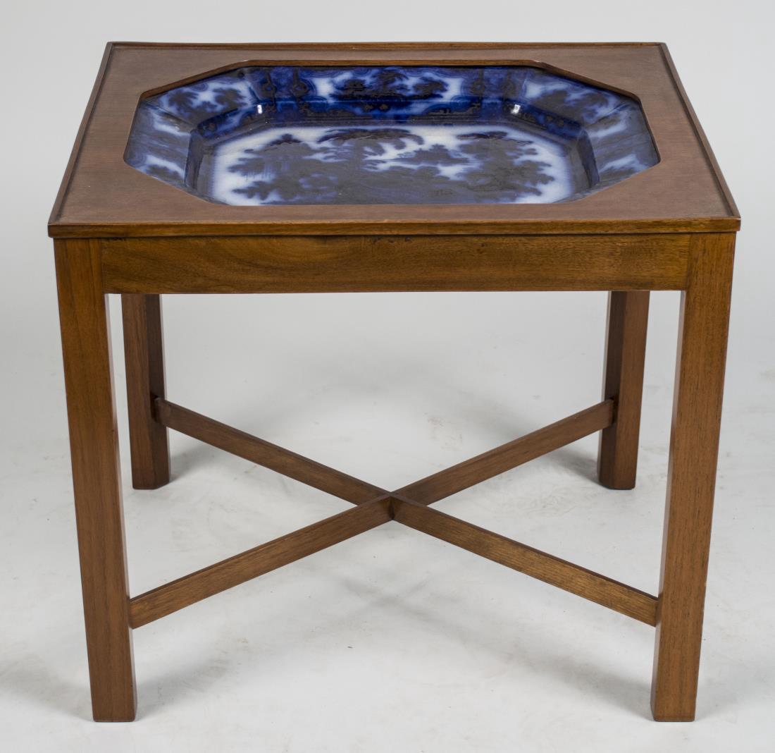 Flow Blue Ceramic Tray Table: Octagonal tray set in a wood table top on square legs joined by a X stretcher. Height 19 inches, width 20 inches, depth 16 inches. Notice to bidders: Condition reports and additional photographs are p