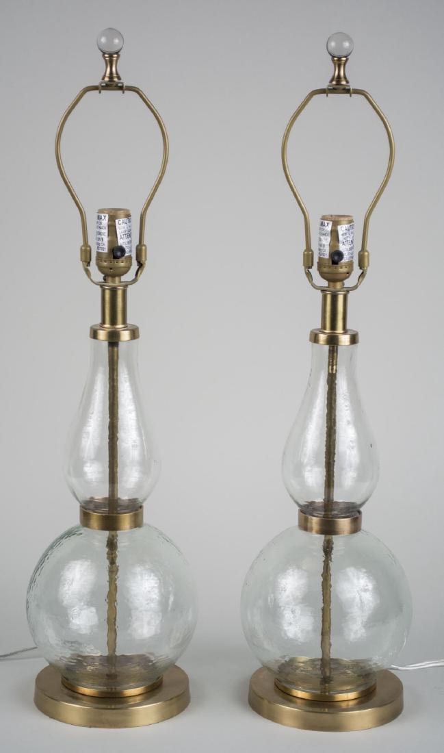 Pair of Glass Lamps: Single light vase form colorless glass lamps. Base, height 15 inches. Notice to bidders: Condition reports and additional photographs are provided by request as a courtesy to our clients, as such any 