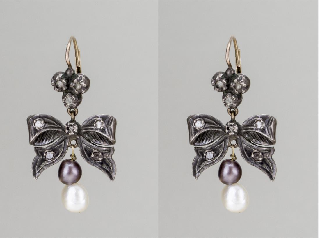 Pearl Bow Earrings: 10k gold and silver ear wires, designed as a bow ribbon suspending a black and a white pearl. 1 1/2 x 7/8 inches, 9.0 grams. Notice to bidders: Condition reports and additional photographs are provide