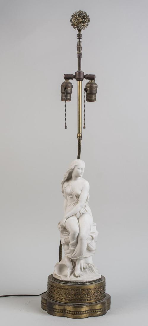 Italian Bisque Porcelain Figural Lamp: Two light lamp with a female figure in a diaphanous dress. Figure, height 16 inches. Notice to bidders: Condition reports and additional photographs are provided by request as a courtesy to our client