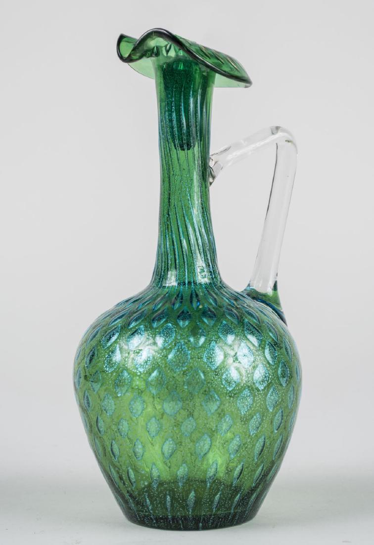 Loetz Style Iridescent Glass Ewer: Blue-green iridescent glass ewer with colorless glass handle. Height 10 1/4 inches. Notice to bidders: Condition reports and additional photographs are provided by request as a courtesy to our clients