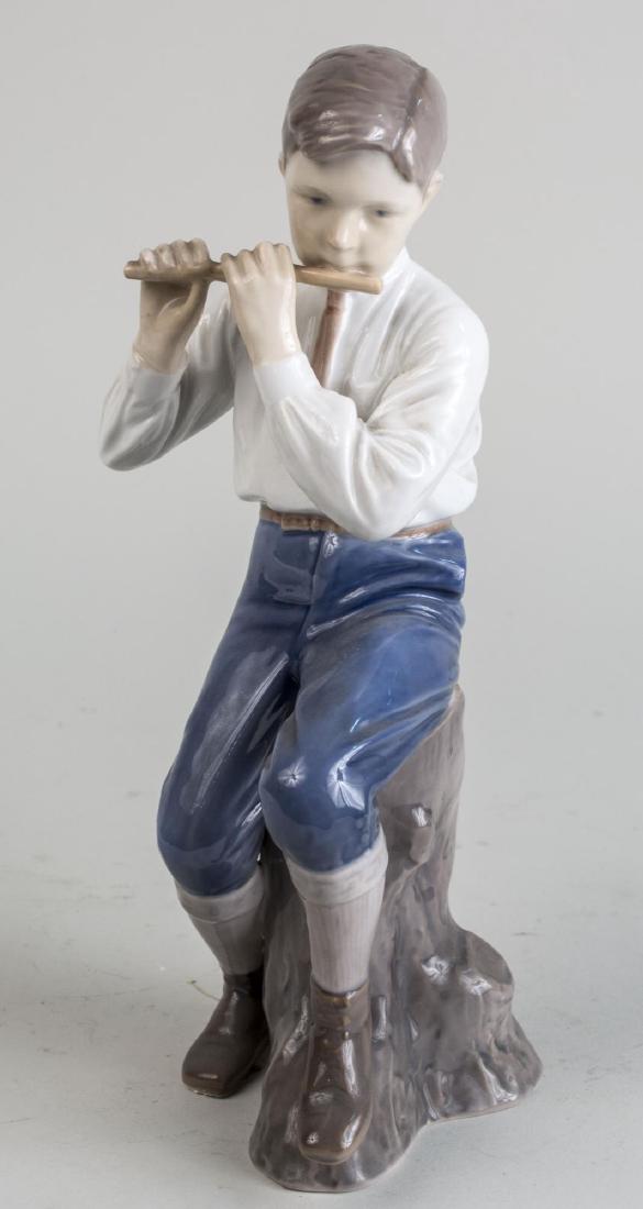 Bing & Grondahl Porcelain Figure: Boy playing a flute. Height 12 inches. Notice to bidders: Condition reports and additional photographs are provided by request as a courtesy to our clients, as such any condition report is only an opi