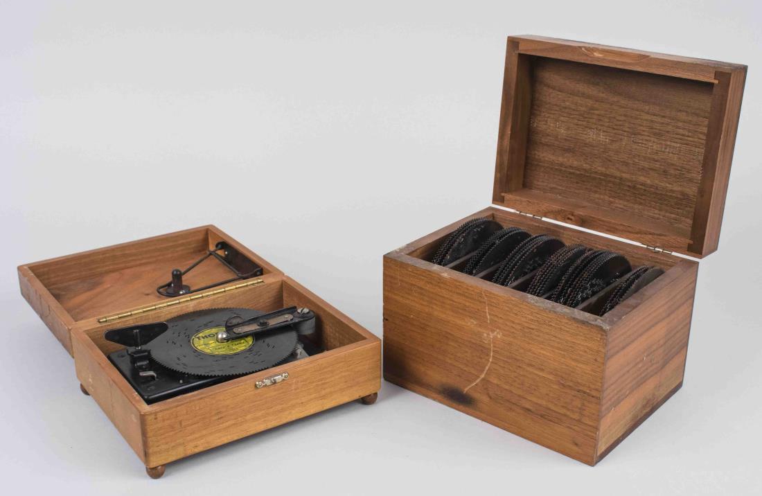 Thorens Disc Music Box: Swiss wood music box, together with a separate box of twenty-eight discs. Music box, height 3 inches, width 7 1/8 inches, depth 5 3/4 inches. Notice to bidders: Condition reports and additional photog