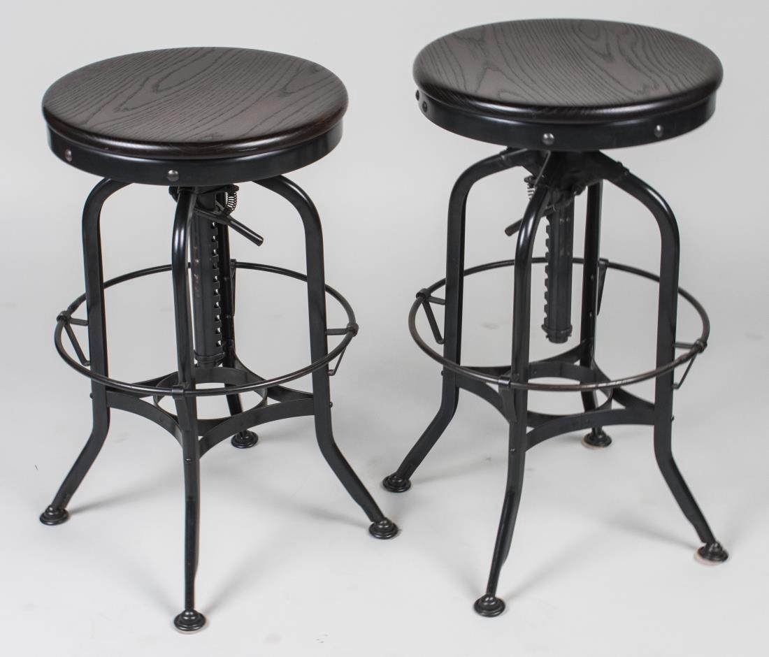 Pair of Wood Seat Steel Base Industrial Bar Stools: Adjustable. Height 27 inches, diameter 16 inches. Provenance: Estate of Sandy Gallin Notice to bidders: Condition reports and additional photographs are provided by request as a courtesy to our client