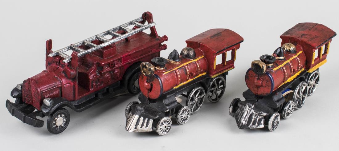 Three Cast Iron Toys: Fire engine with ladder and two train engines. Fire engine, length 10 inches. Notice to bidders: Condition reports and additional photographs are provided by request as a courtesy to our clients, as s