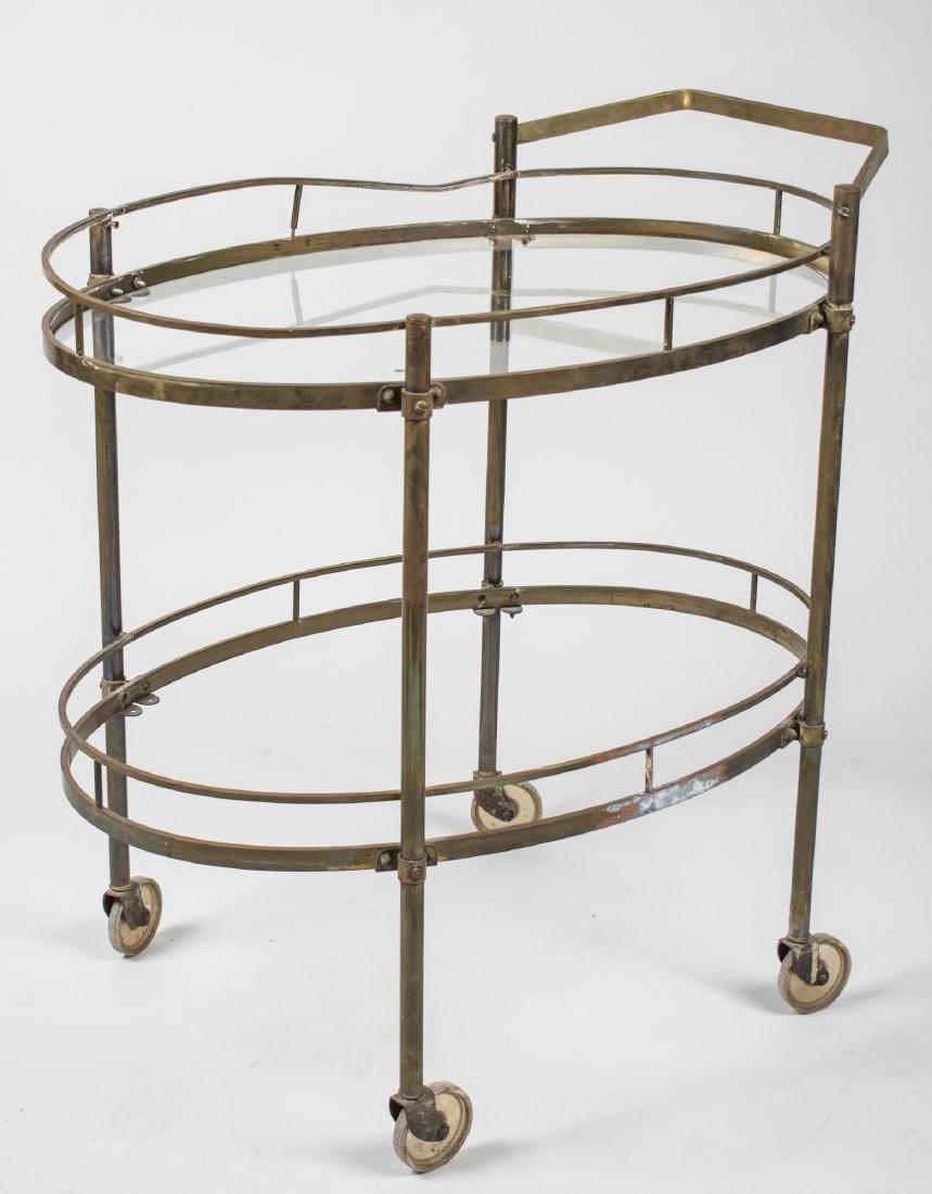 Brass and Glass Tea Cart: Two tier cart with two oval glass shelves, on casters. Height 31 inches, width 30 inches, depth 19 1/2 inches. Notice to bidders: Condition reports and additional photographs are provided by request a