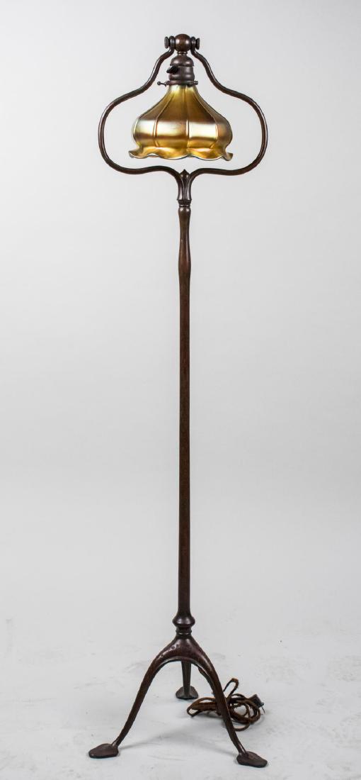 Tiffany Floor Lamp: Favrille style glass shade, columnar support on a tripod vase, signed Tiffany Studios on the base. Height 54 inches. Notice to bidders: Condition reports and additional photographs are provided by req