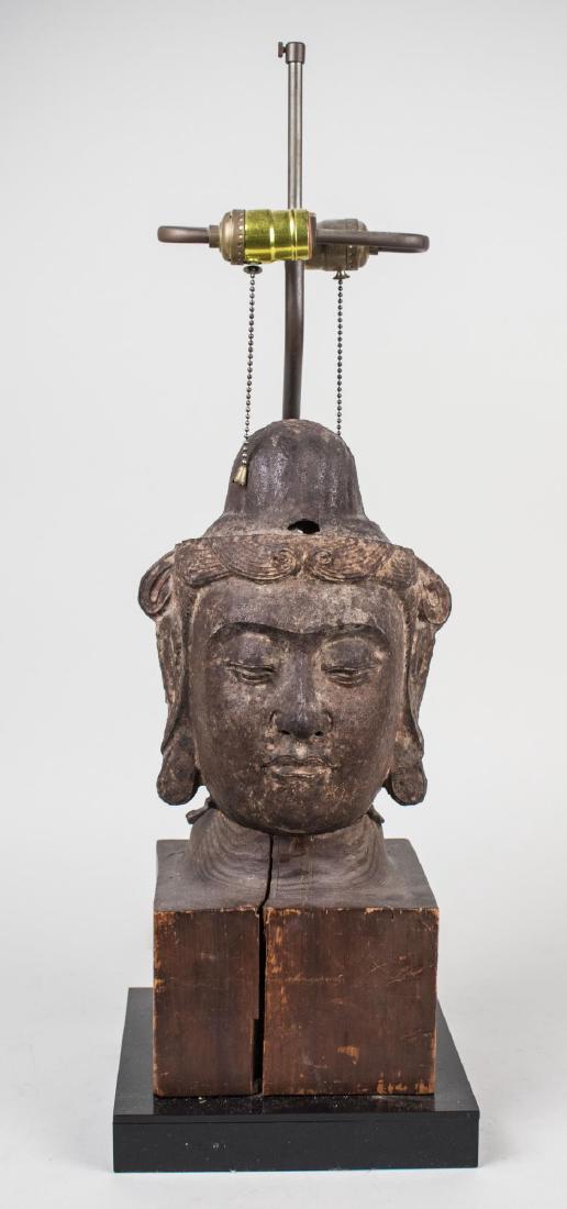 Chinese Iron Buddha Lamp: Two light lamp, base mounted with an iron Buddha head. Base, height 16 1/2 inches. Notice to bidders: Condition reports and additional photographs are provided by request as a courtesy to our clients,
