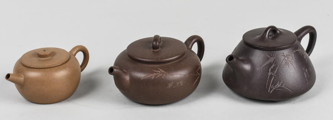 Three Chinese Earthenware Teapots: All marked on the bottom. Largest, height 2 3/4 inches. Notice to bidders: Condition reports and additional photographs are provided by request as a courtesy to our clients, as such any condition repo