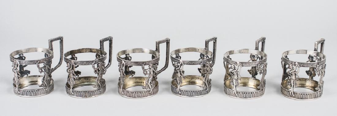 Set of Six Continental Silver Cup Holders: Neoclassical decoration of females. Height over handles, 3 inches, total 650 grams. Notice to bidders: Condition reports and additional photographs are provided by request as a courtesy to our clients