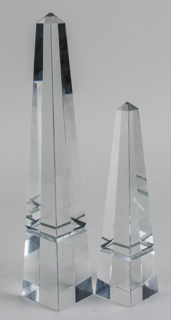Two Colorless Glass Obelisks: Of typical form. Taller, height 14 inches. Notice to bidders: Condition reports and additional photographs are provided by request as a courtesy to our clients, as such any condition report is only an