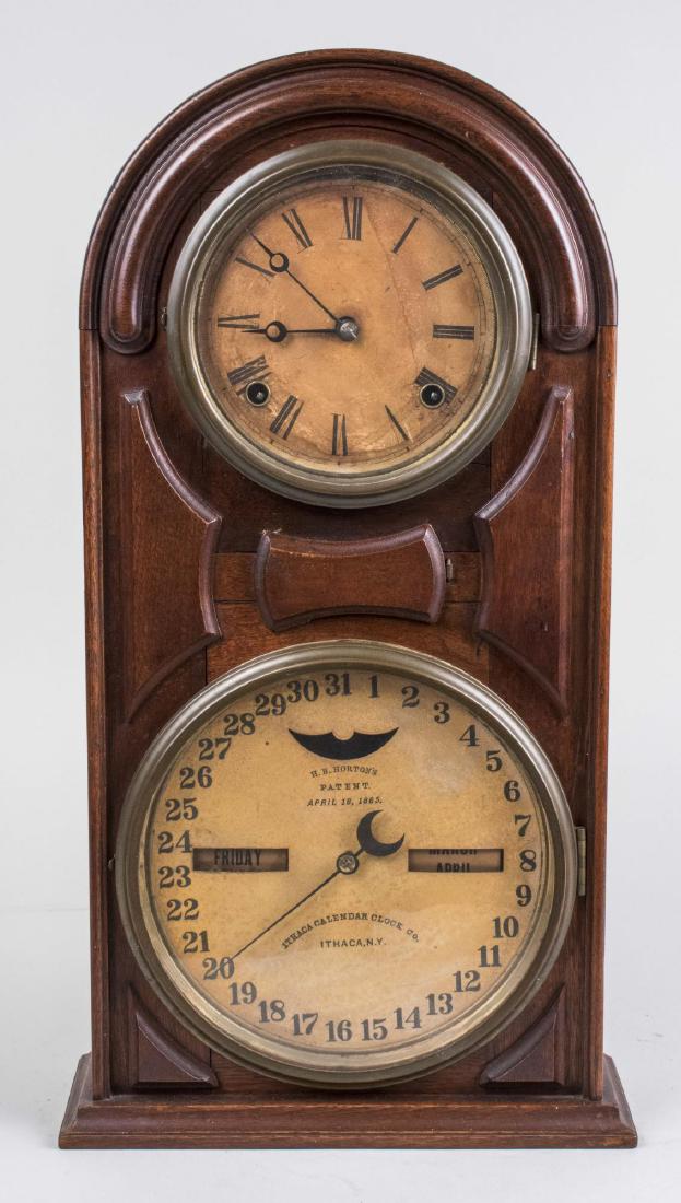 Ithaca Calendar Clock: Paper dial with Roman numerals, above a second dial with calendar and day and date aperture. Height 20 inches. Notice to bidders: Condition reports and additional photographs are provided by request a
